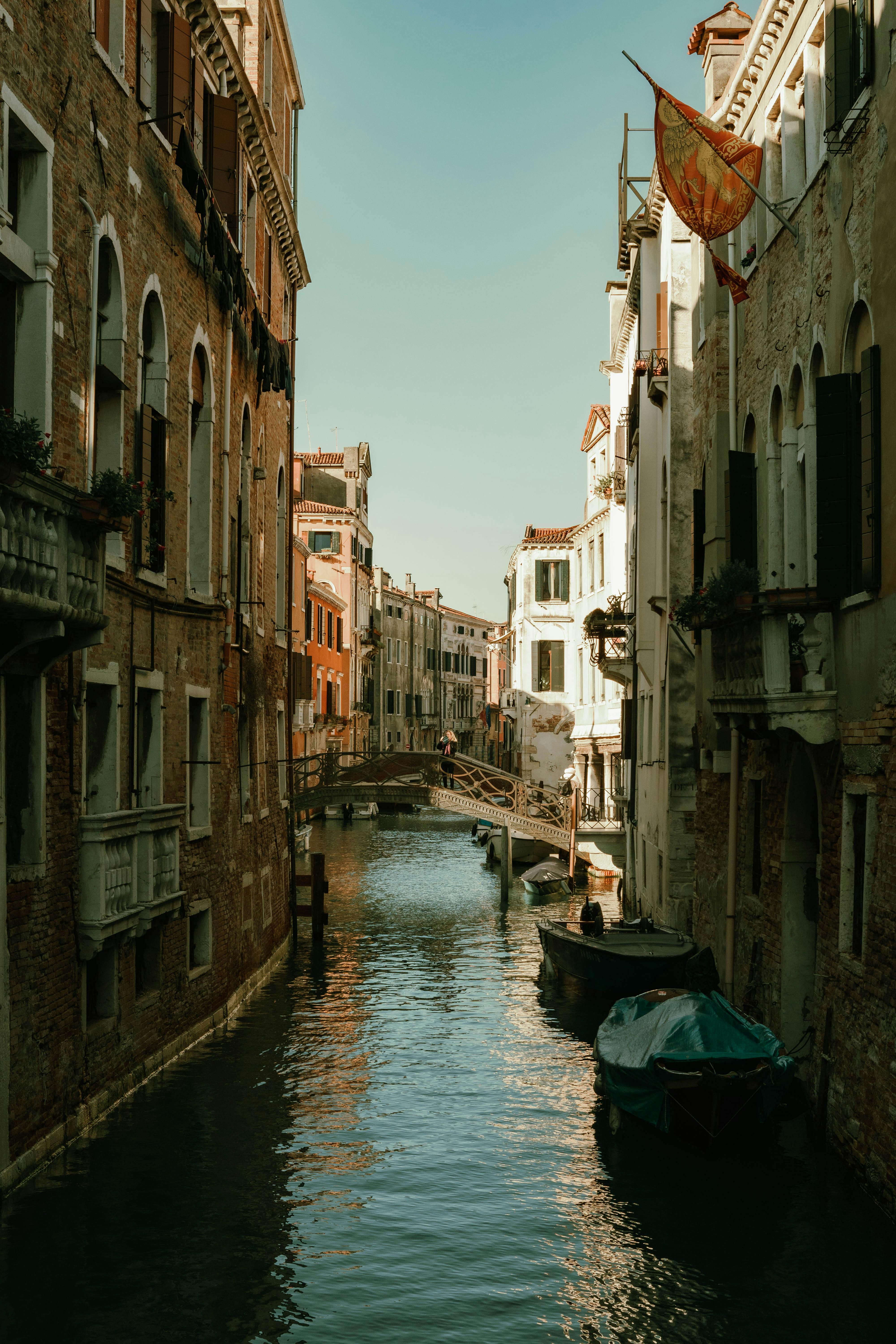Idyllic view of a canal in Venice featuring rustic buildings and a small bridge reflecting the serene water.