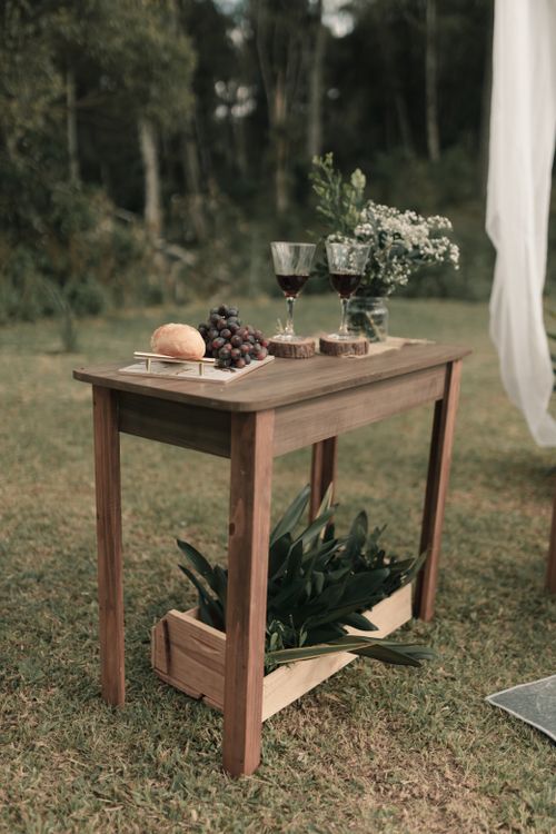 Free Outdoor wooden table with wine glasses, grapes, and bread on grass. Stock Photo