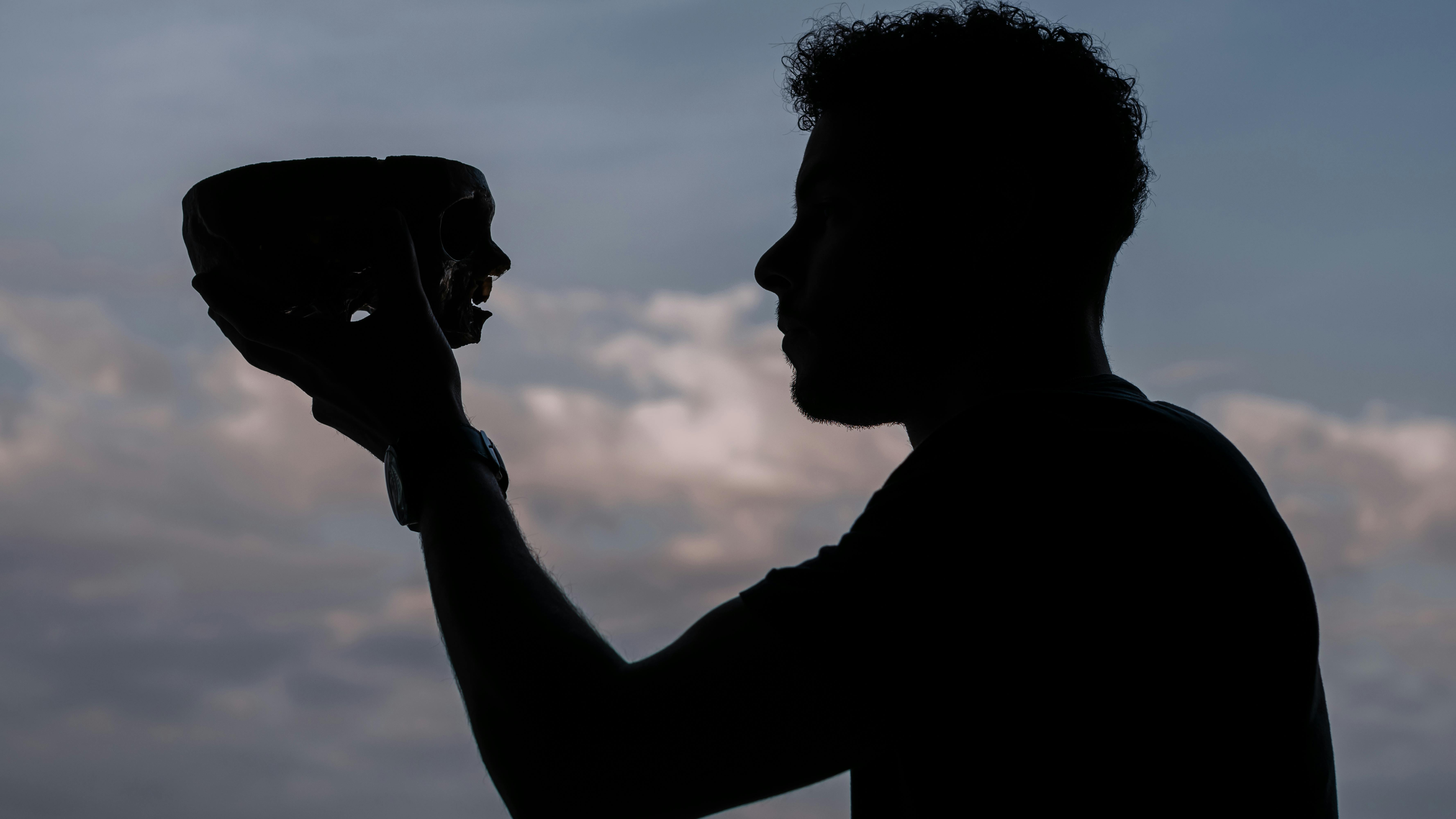 Gratuit O siluetă dramatică a unui bărbat care ține un craniu pe cerul crepuscular din Buenos Aires. Fotografie de stoc