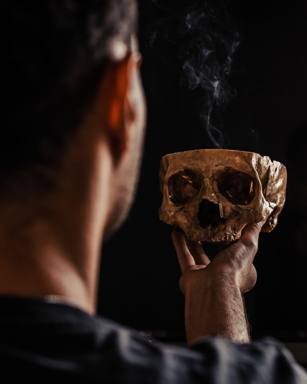 Hamlet holding the skull aloft in stage smoke