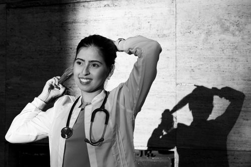Free A black and white portrait of a smiling female doctor in Buenos Aires, with her shadow on the wall. Stock Photo
