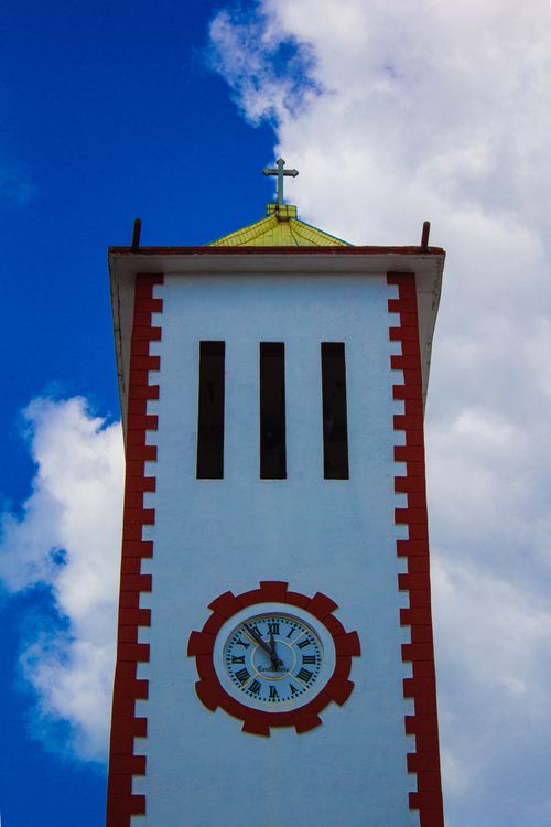 Free Majestic tower with clock and cross against a vibrant blue sky in Metlaltoyuca, Mexico. Stock Photo