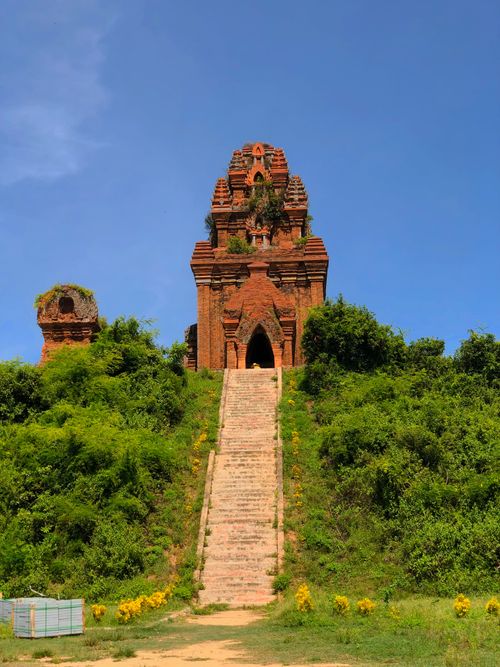 Free Historic Cham temple with vibrant greenery and clear blue sky, showcasing ancient architecture. Stock Photo