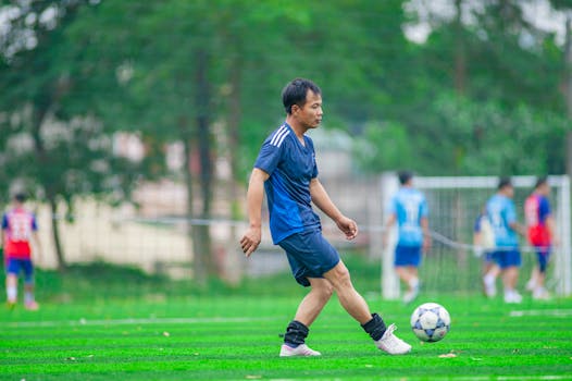 Amateur soccer player practicing on a field in Hanoi, Vietnam with teammates in the background.