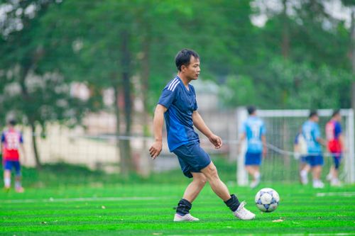Free Amateur soccer player practicing on a field in Hanoi, Vietnam with teammates in the background. Stock Photo