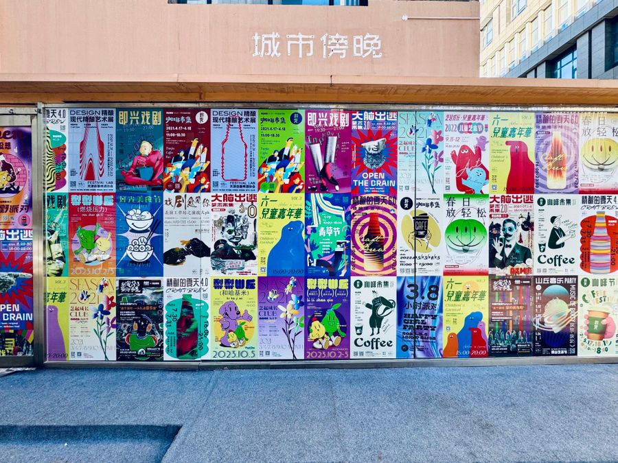Street wall covered with dozens of colourful printed posters
