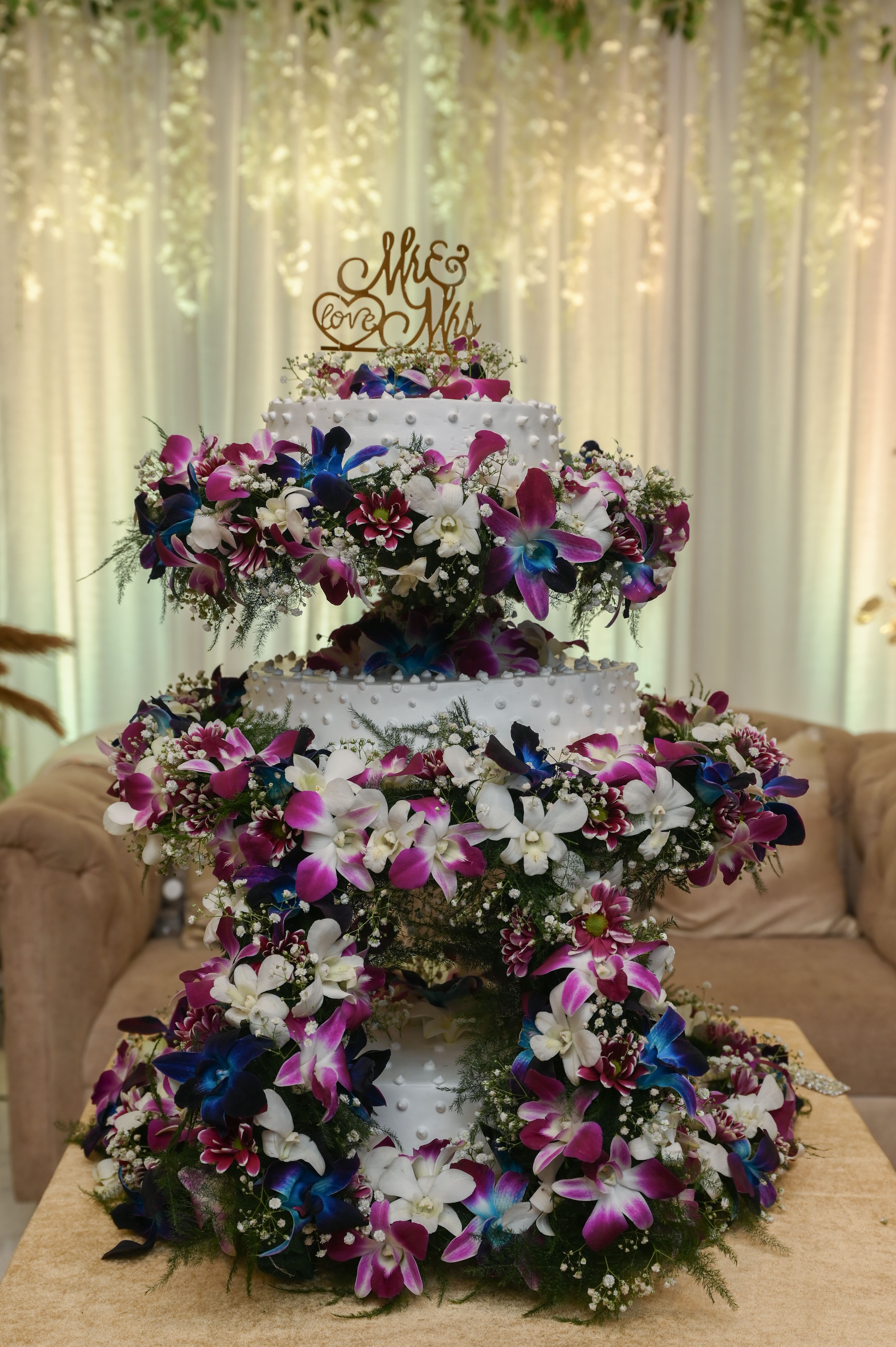Three-tiered wedding cake adorned with vibrant purple and white flowers, perfect for an elegant celebration.