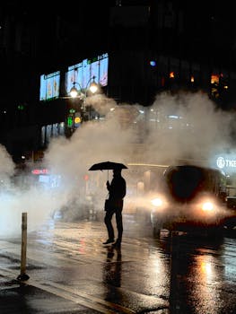 A dramatic night scene in New York City with rain and steam creating a mysterious urban atmosphere.