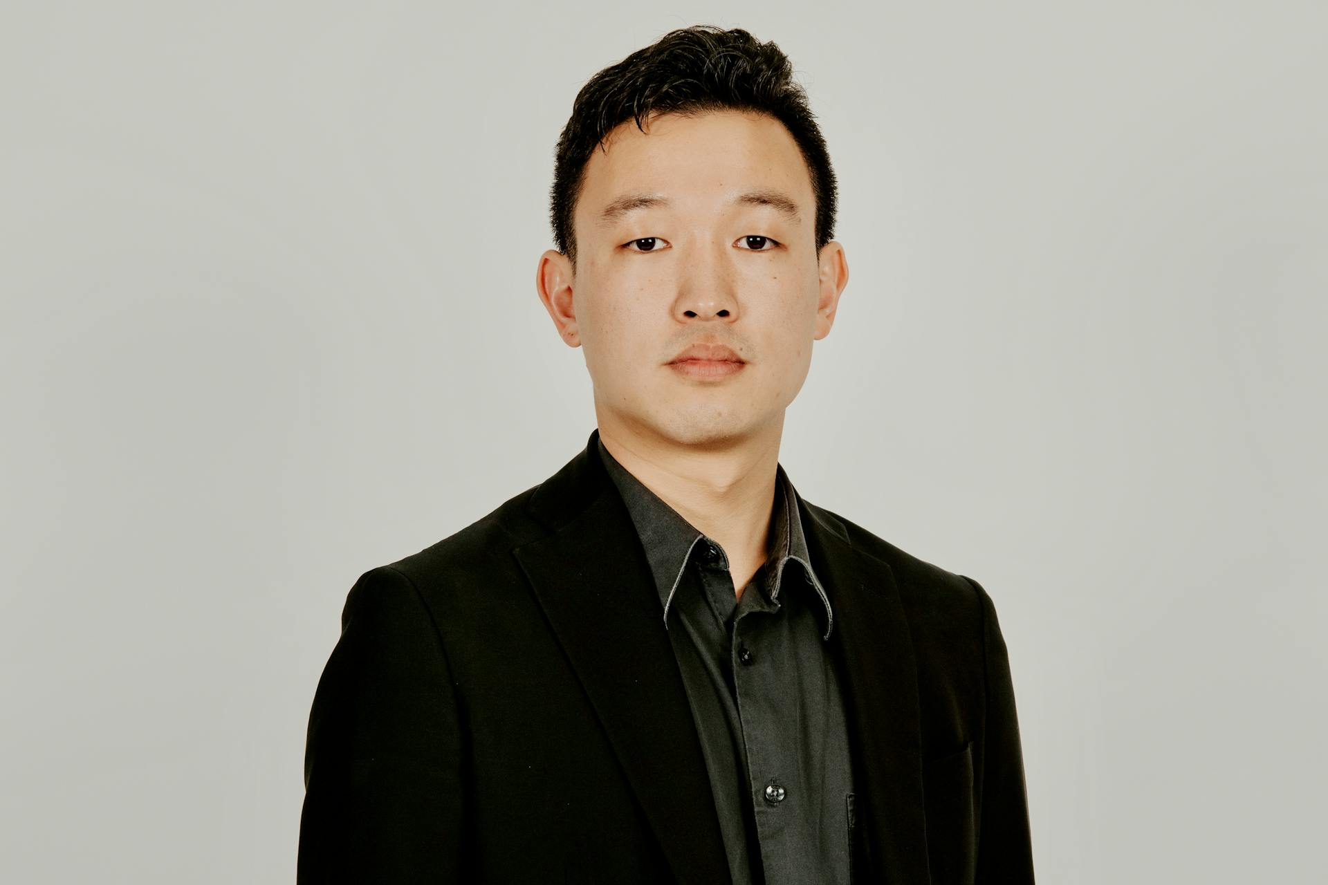 Portrait of a young adult in a formal suit, isolated on a neutral background.