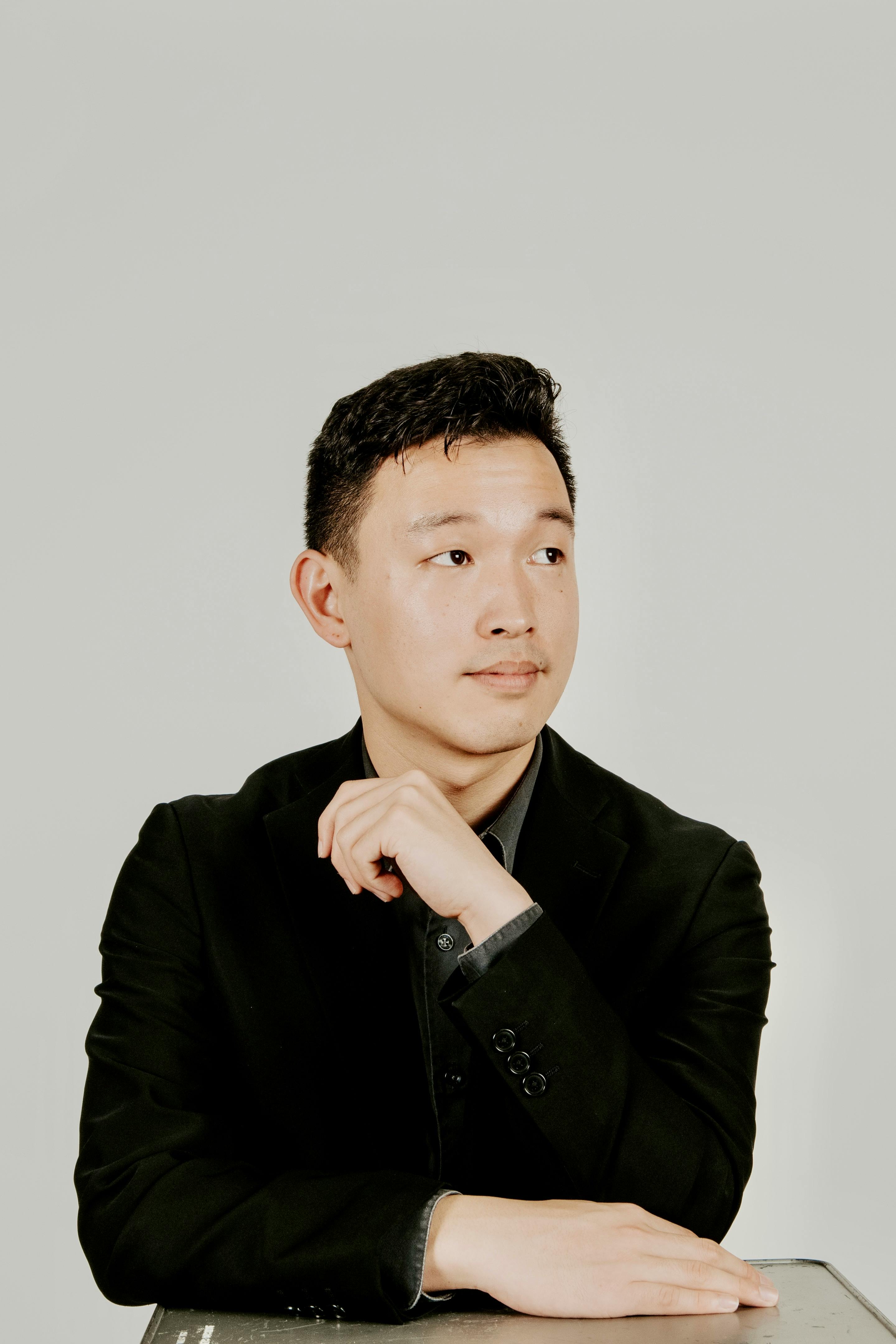 免費 一個穿著黑色西裝的男人的優雅肖像，在中性背景下看著一旁。 圖庫相片