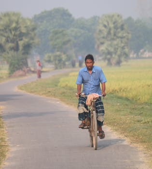 A man rides a bicycle down a rural road in Mirpur, Bangladesh.