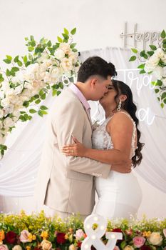 Bride and groom sharing a romantic kiss at a beautifully adorned wedding ceremony.
