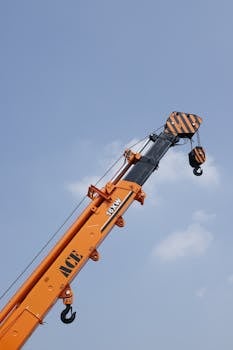 Close-up of ACE 16XW hydraulic crane arm against a clear blue sky.