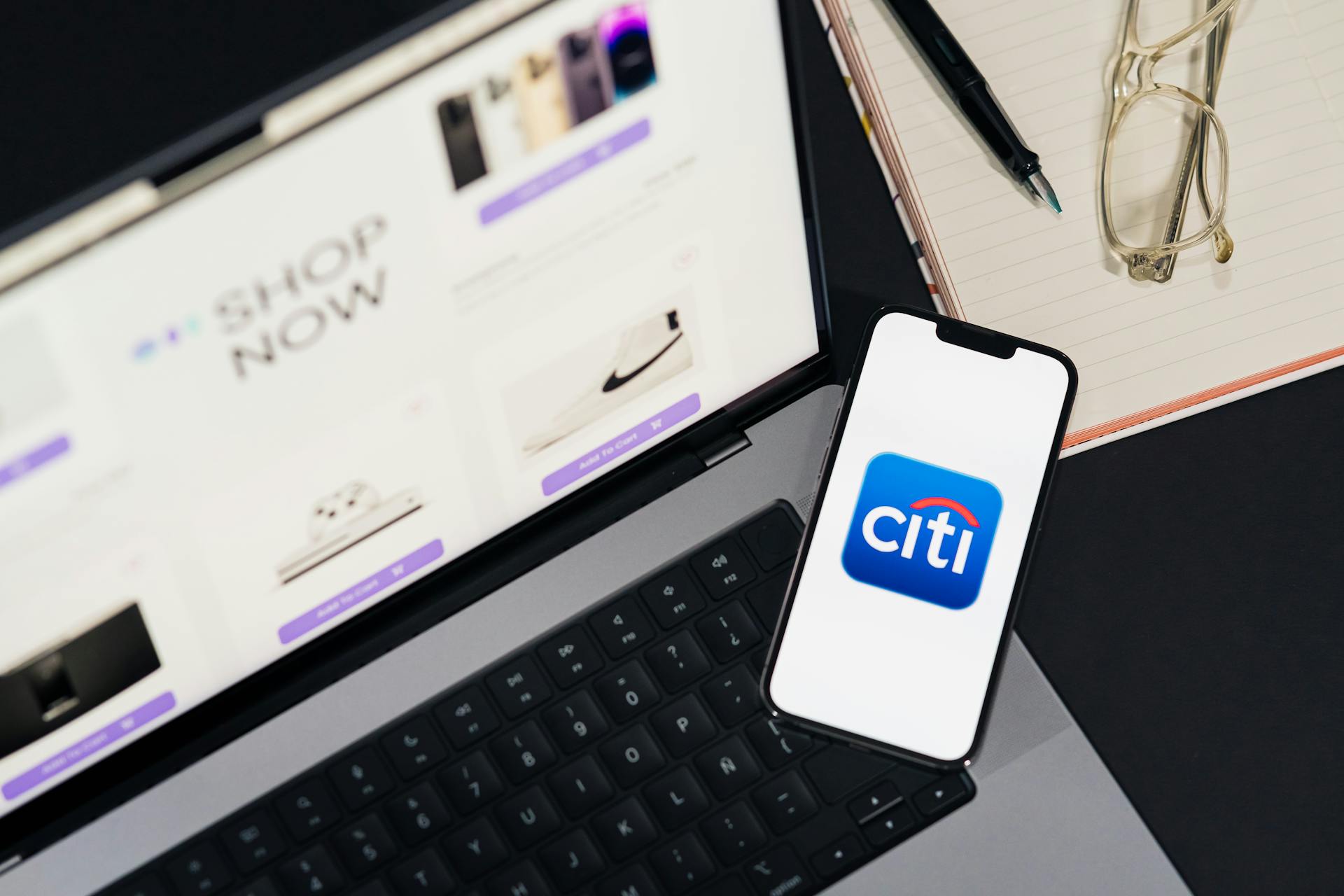 Laptop and smartphone showcasing online shopping and Citi mobile banking app