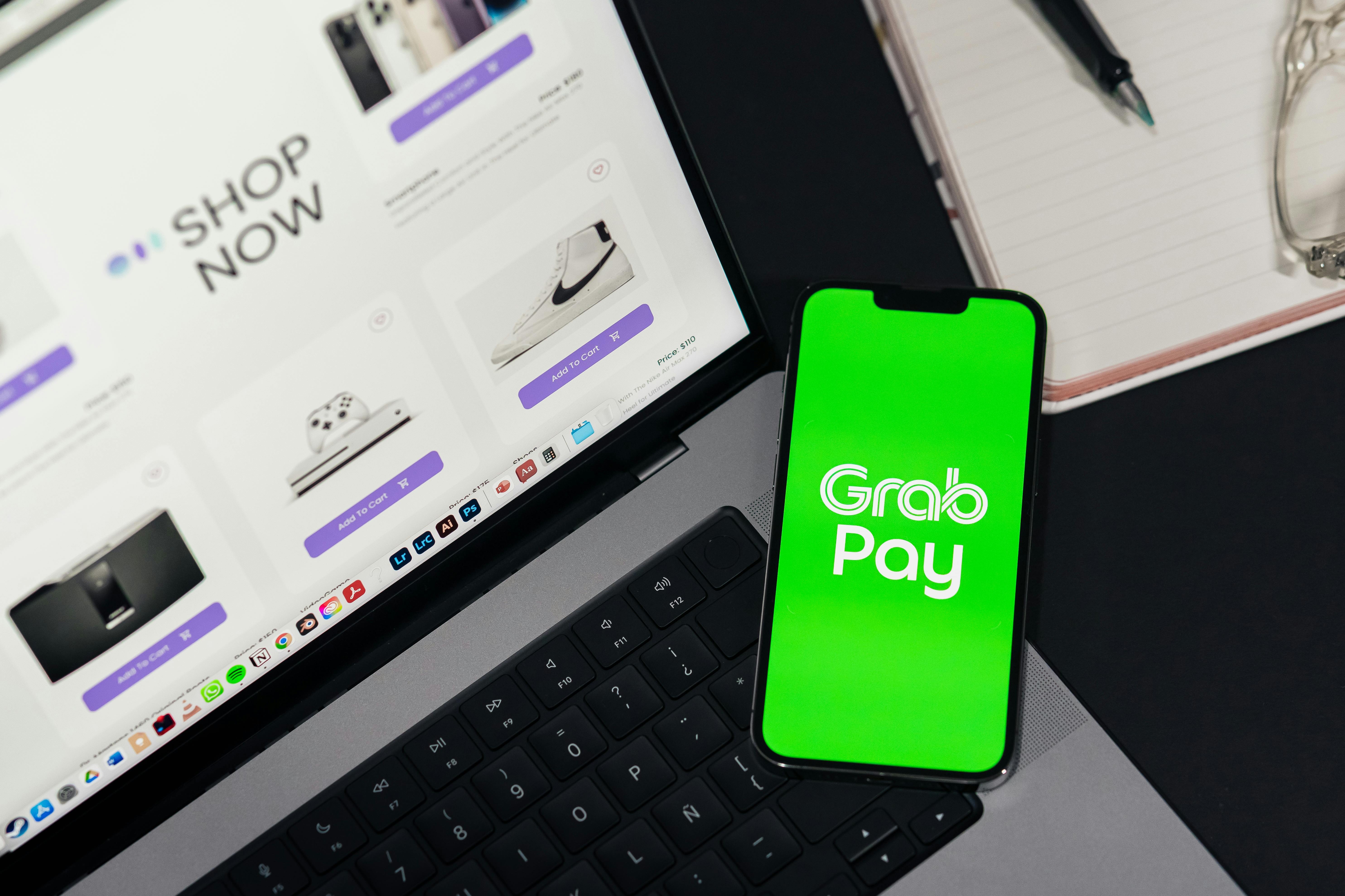Laptop displaying online store with GrabPay app open for seamless mobile payments.