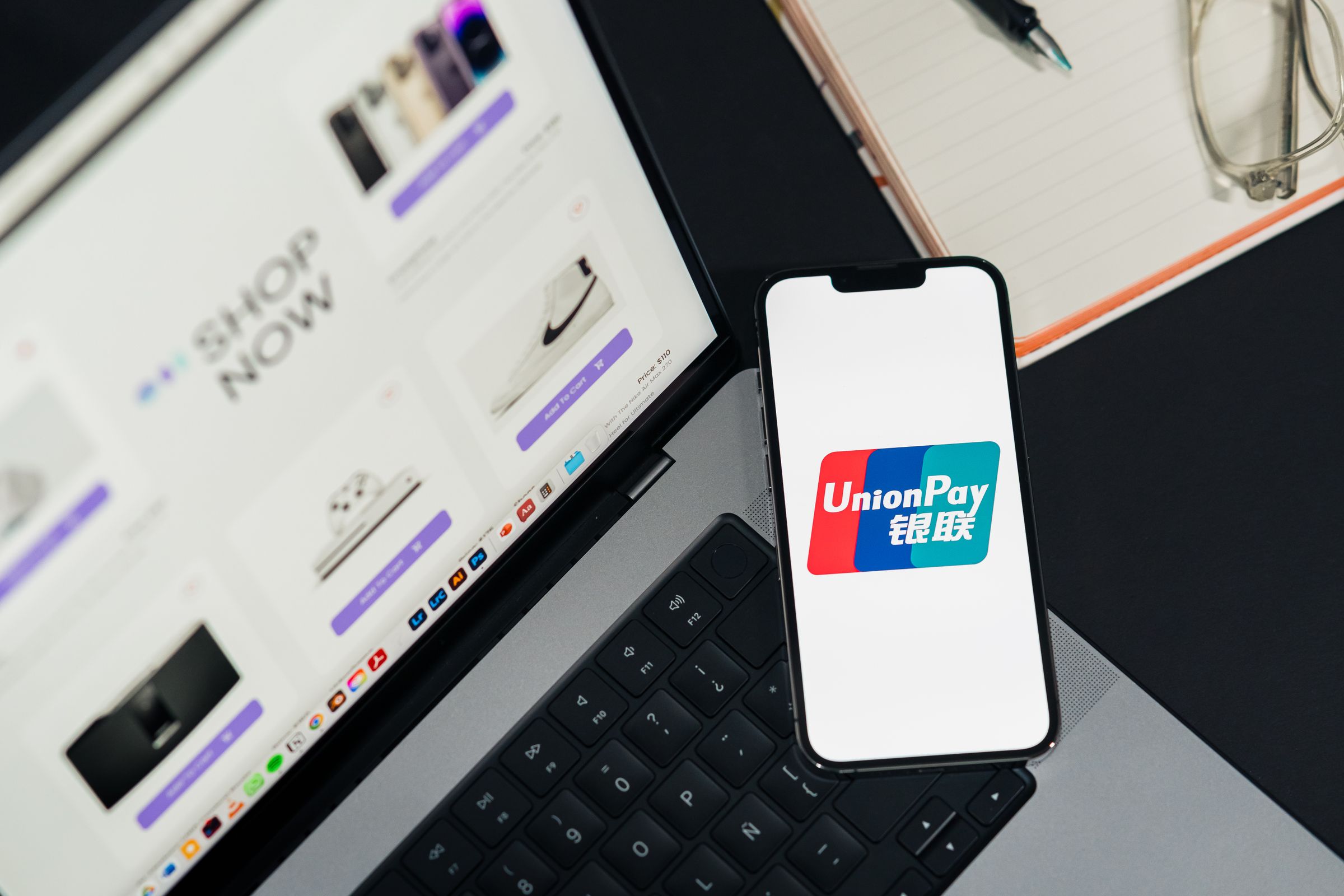 A mobile payment app open on a smartphone next to a laptop during online checkout