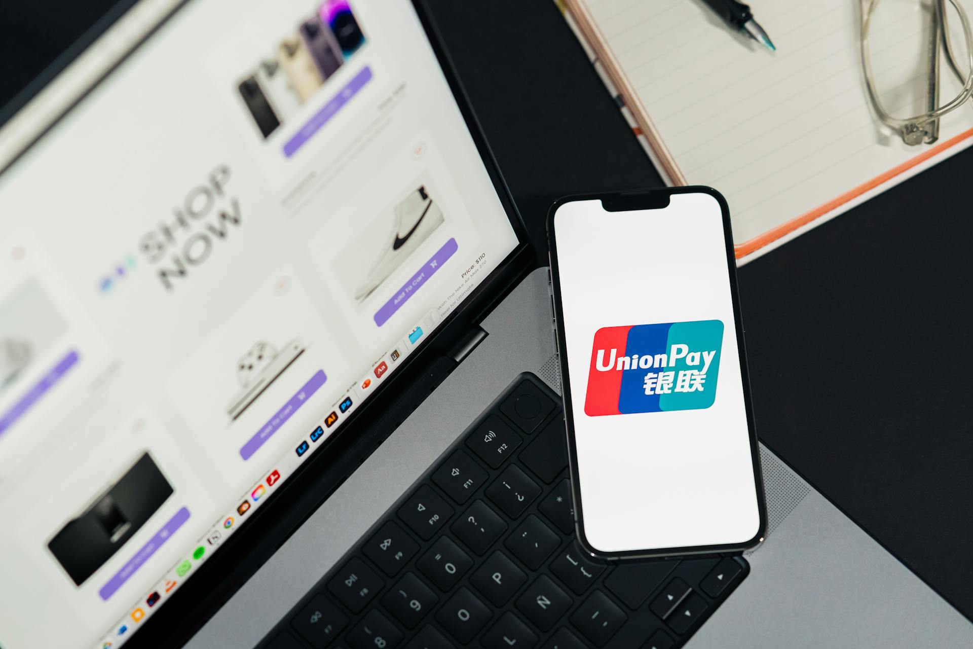 UnionPay logo displayed on a smartphone next to a laptop with an online shopping page open.