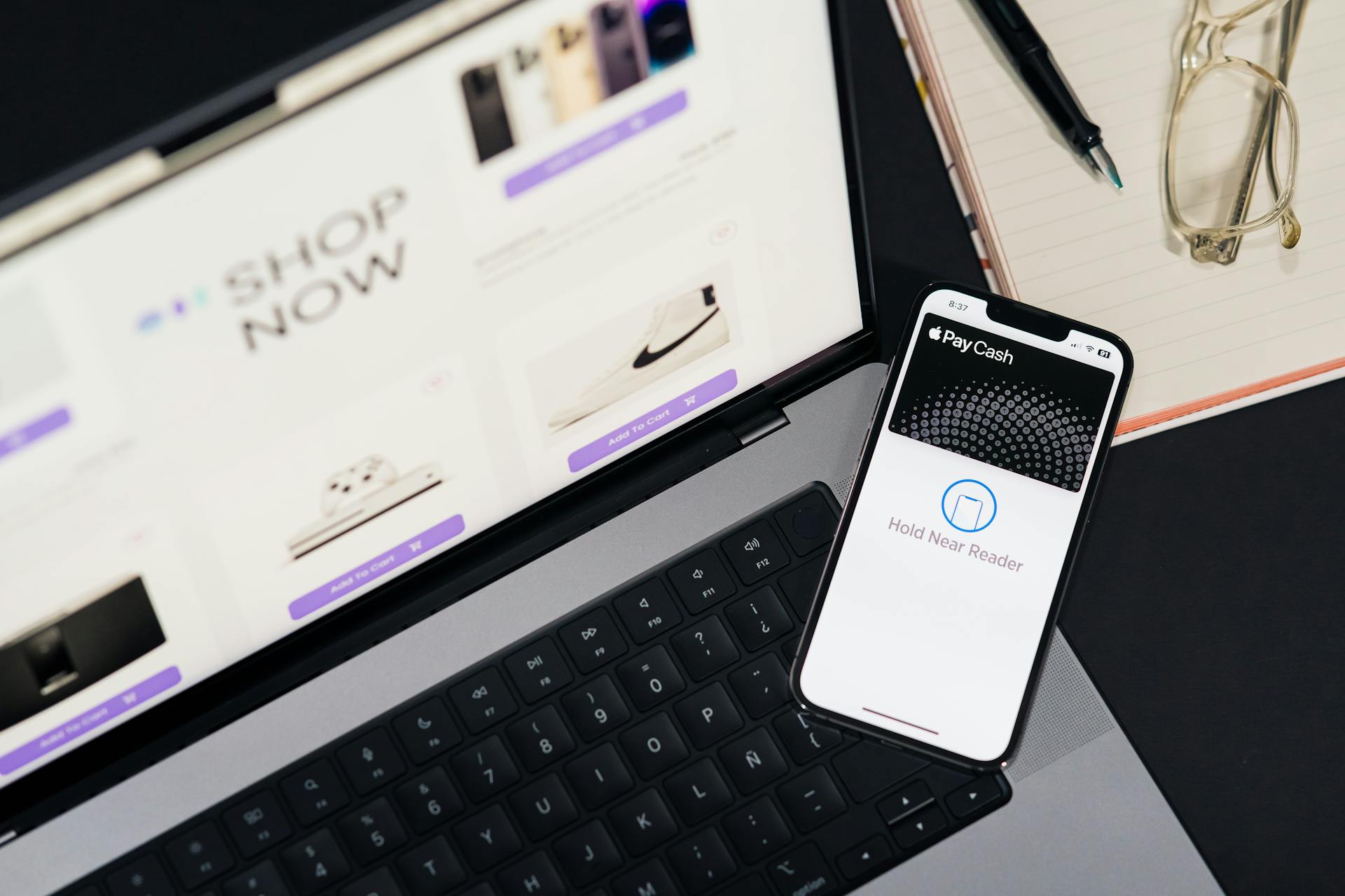 Laptop and smartphone showcasing online shopping and mobile payment setup on desk.