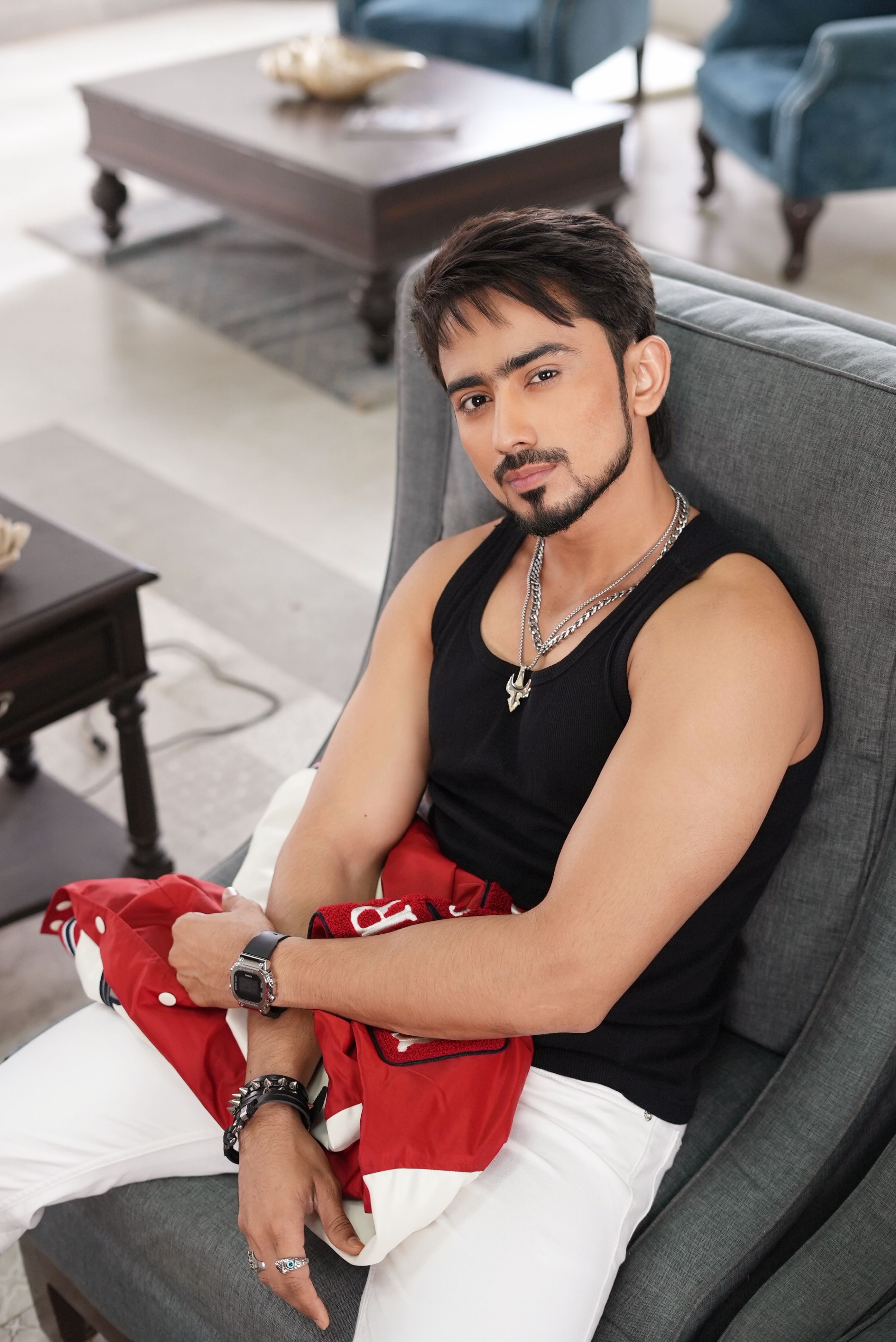 Stylish young man sitting in a modern living room wearing casual outfit, urban vibe.