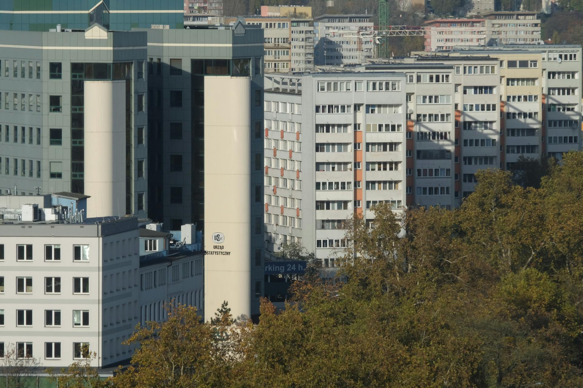 Aerial view of modern high-rise apartment buildings amidst greenery in an urban setting, captured during the day.