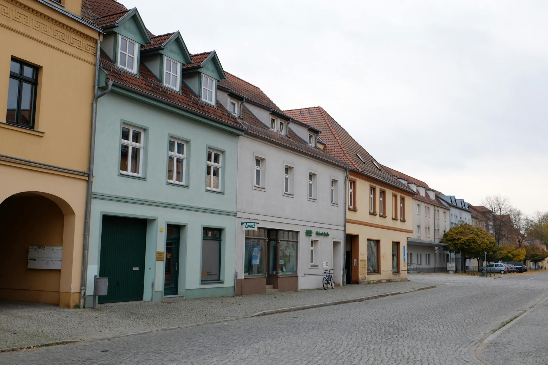 A picturesque European street lined with pastel-colored buildings and a cobblestone road.