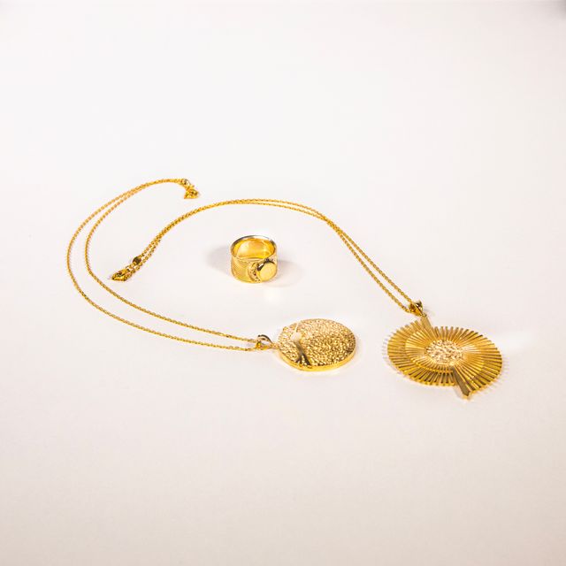 Gold pendant necklace on a neutral surface — photo by Yusuf Celik on Pexels