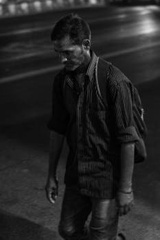 一张男人夜晚独自走在街上的单色图像