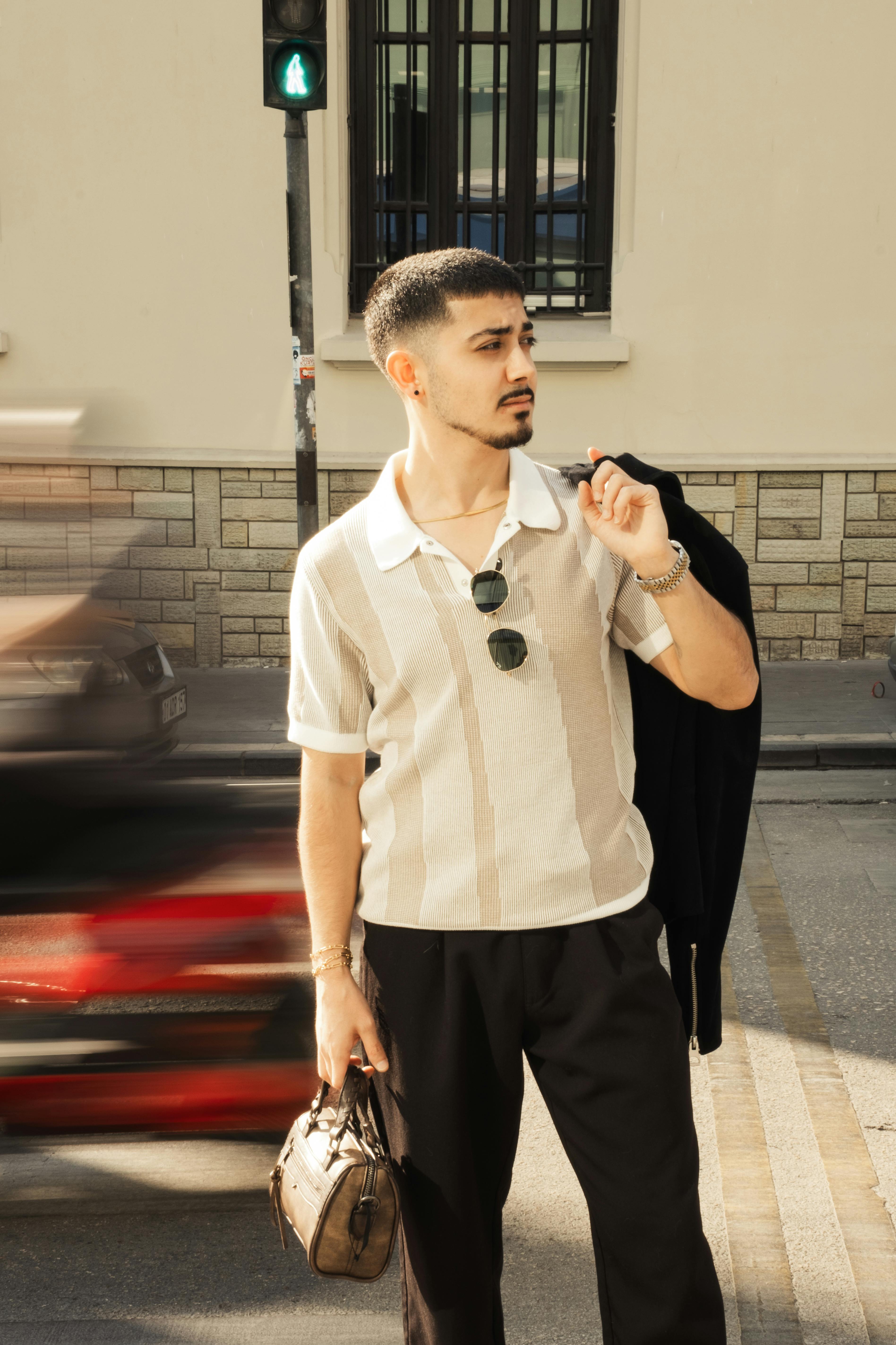 Gratis Hombre elegante sosteniendo una chaqueta en el hombro en la ciudad con tráfico borroso pasando. Foto de stock