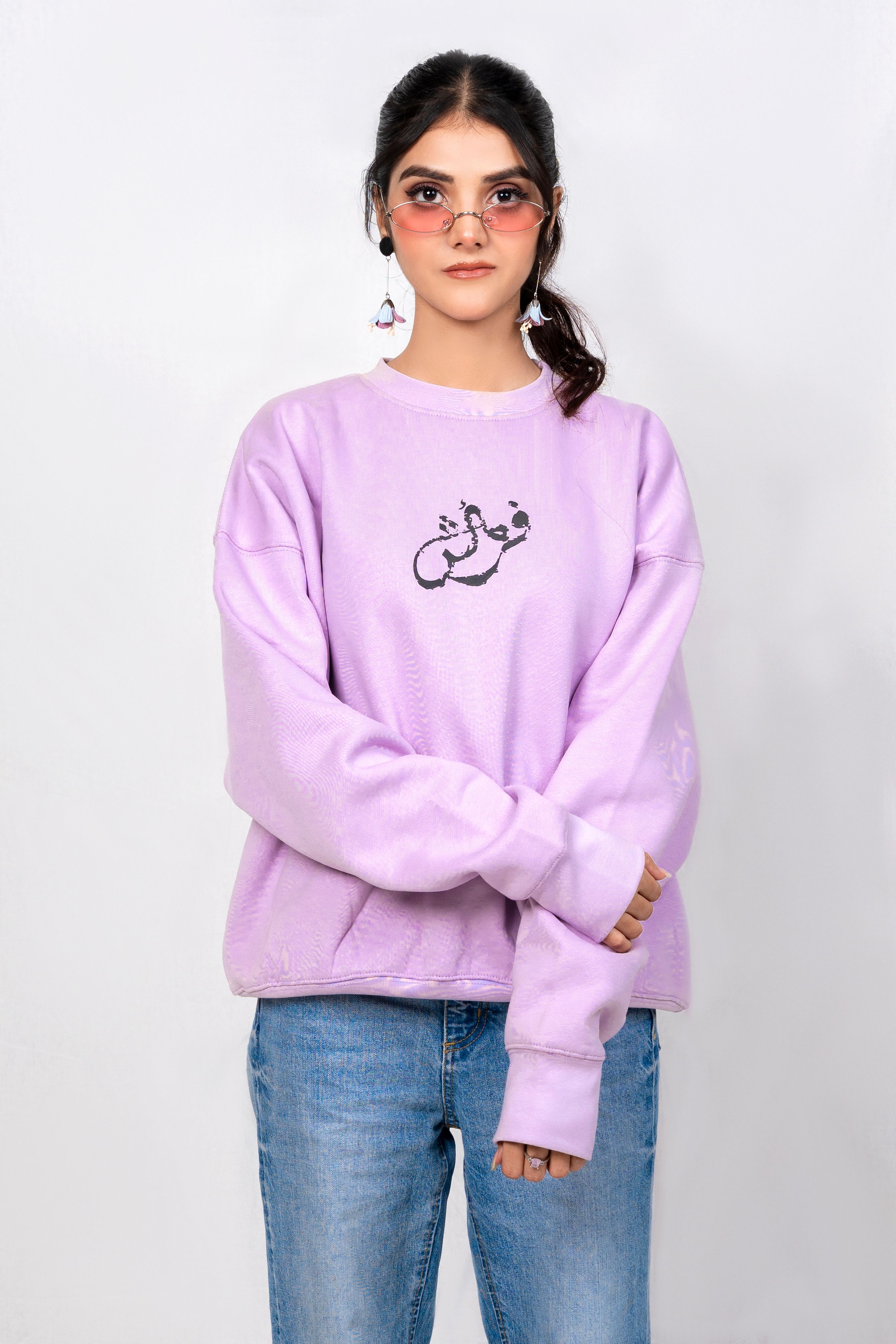 Trendy young woman in a pastel sweater posing against a plain background.