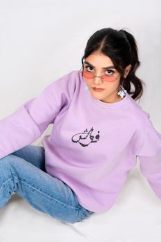 Fashionable young woman in lavender sweatshirt and jeans with pink sunglasses