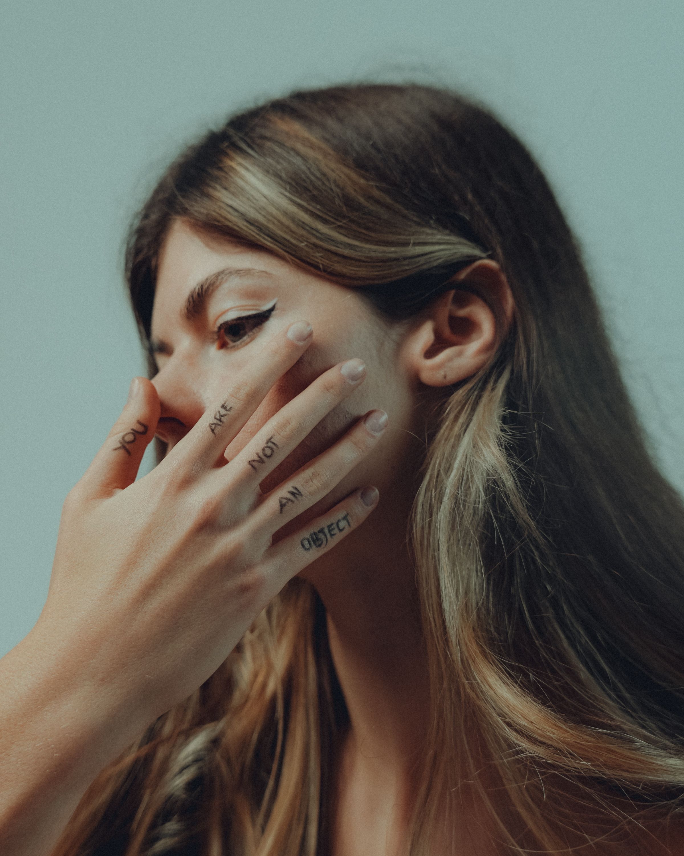 Close-up portrait of a woman with empowering text on her fingers. Thought-provoking and introspective.