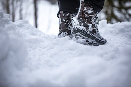 Close-up of boots stepping in deep snow, showcasing winter footwear in a snowy landscape.