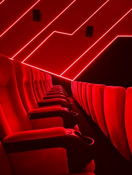 Vibrant theater seats illuminated by red neon lights, showcasing a modern cinema interior.