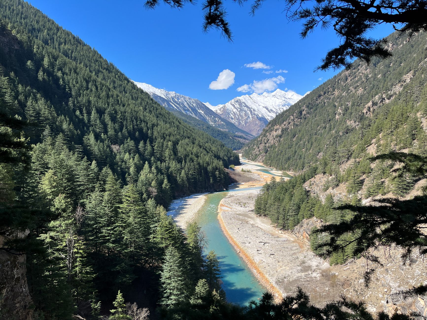 A stunning river meanders through a lush green valley, flanked by towering mountains.