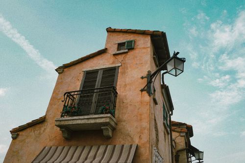Free Rustic house facade with shutters and balcony under a clear sky. Perfect for architecture lovers. Stock Photo
