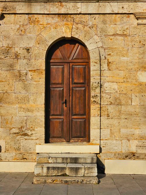 Free A rustic wooden door set in a stone building facade, reflecting historical architecture. Stock Photo