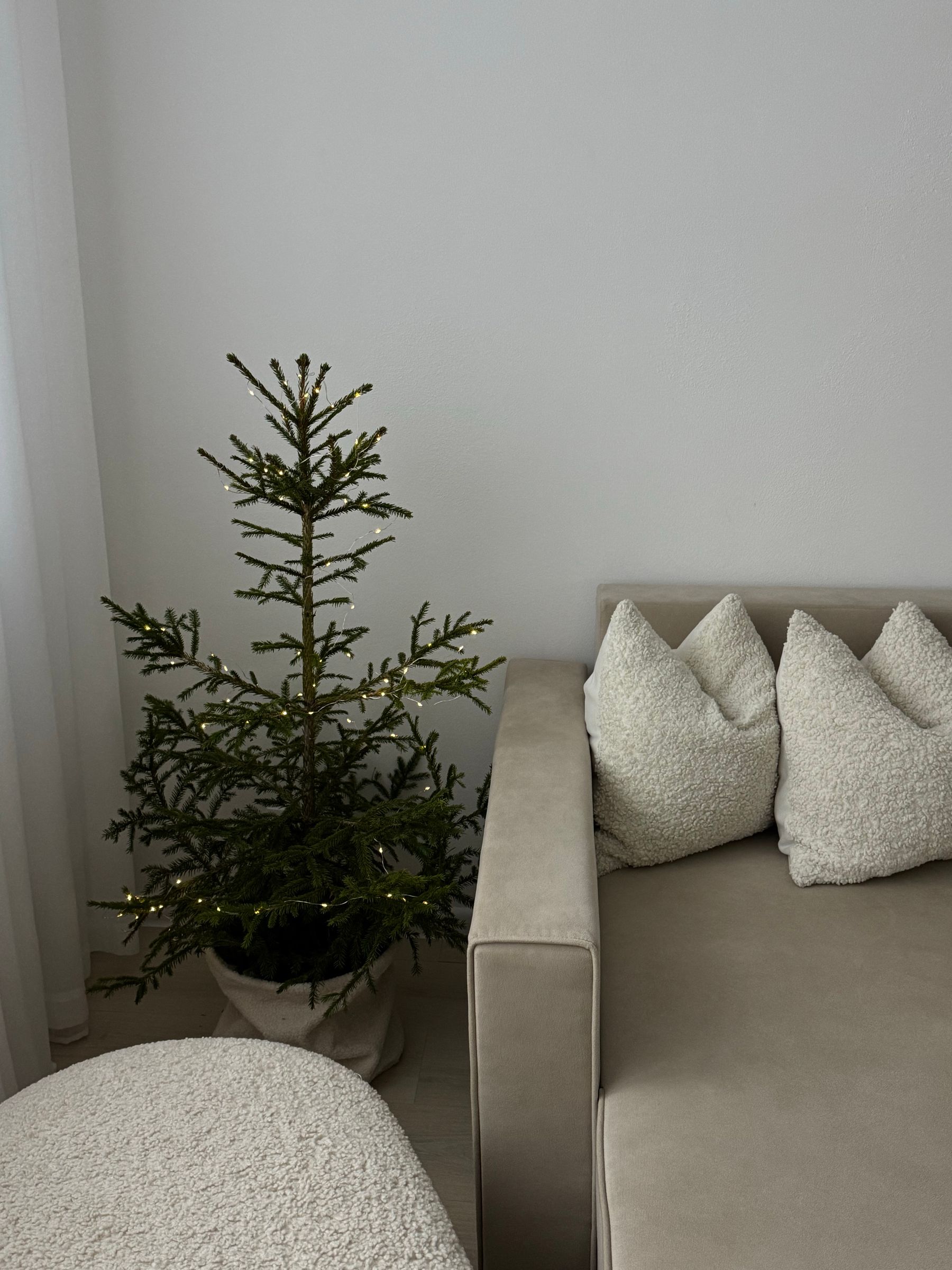 Restrained Christmas tree glowing in a calm neutral living room