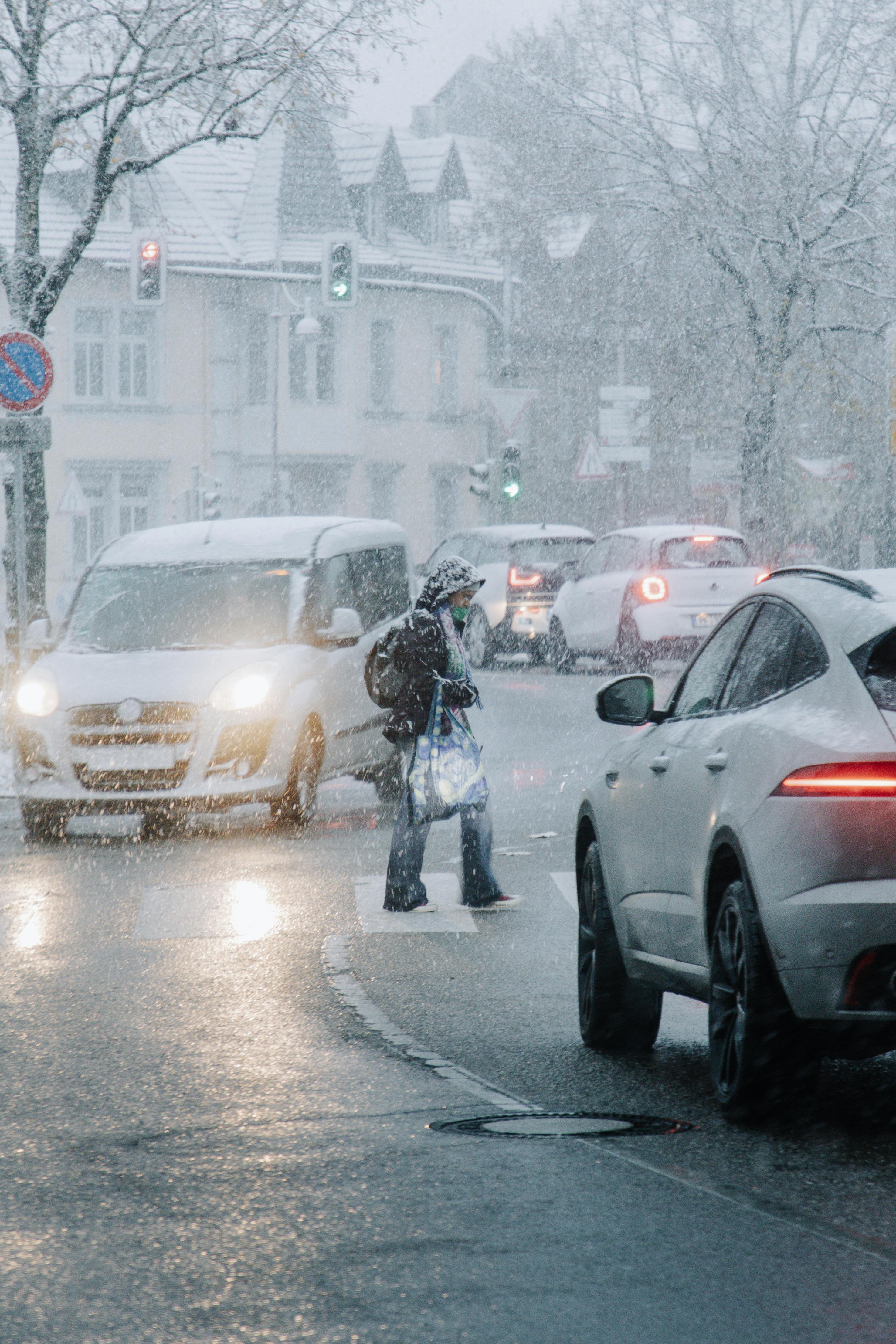 Free Snowfall in Bretten captures a wintery street scene with cars and pedestrians. Stock Photo