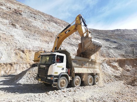 Excavator loading dump truck in a quarry. Industrial mining equipment scene.