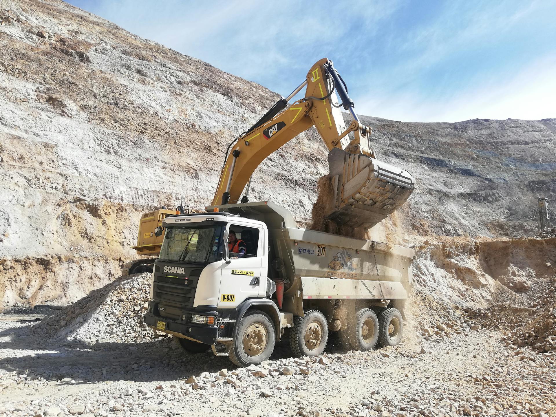 Excavator loading dump truck in a quarry. Industrial mining equipment scene.