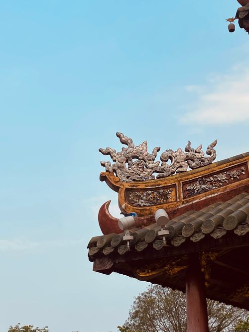Free Close-up of a traditional Asian temple roof with ornate dragon sculptures under a clear sky. Stock Photo