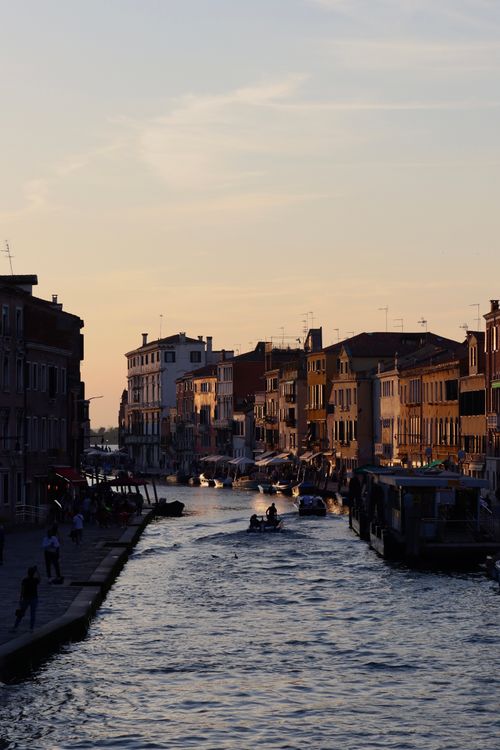 Free Beautiful sunset view of a canal in Venice with historic buildings and boats. Stock Photo