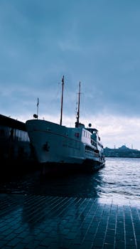 Silhouette of a ferry at the dock against a cloudy Istanbul cityscape.