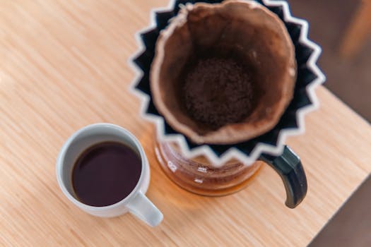 Top view of a stylish pour-over coffee setup with a fresh brewed coffee cup on wooden table.