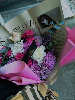 Chic floral bouquet in pink and purple hues, elegantly wrapped with a magazine page.