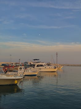 A tranquil scene of boats docked at a marina during a summer evening with a soft sunset.