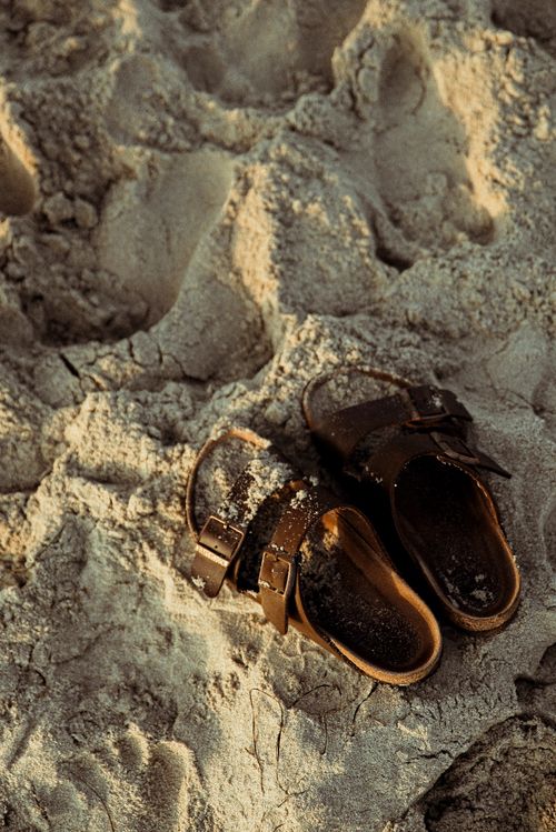 Free Closeup of leather sandals on sandy beach, perfect for summer themes. Stock Photo