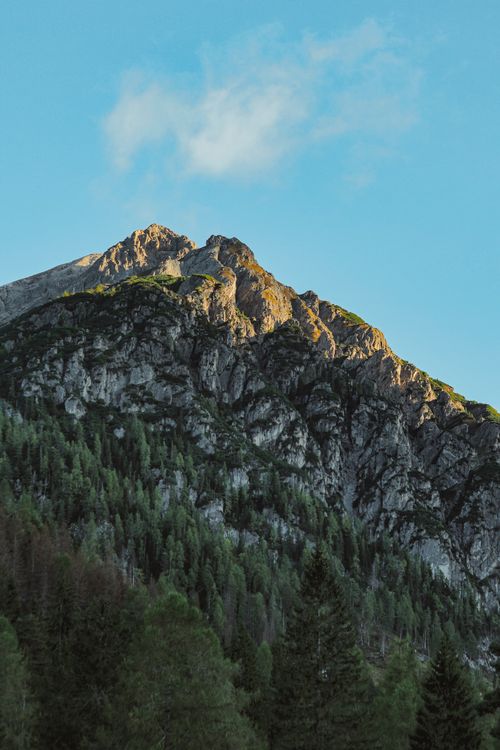 Free Majestic mountain peak in morning light with lush greenery below, capturing nature's beauty. Stock Photo
