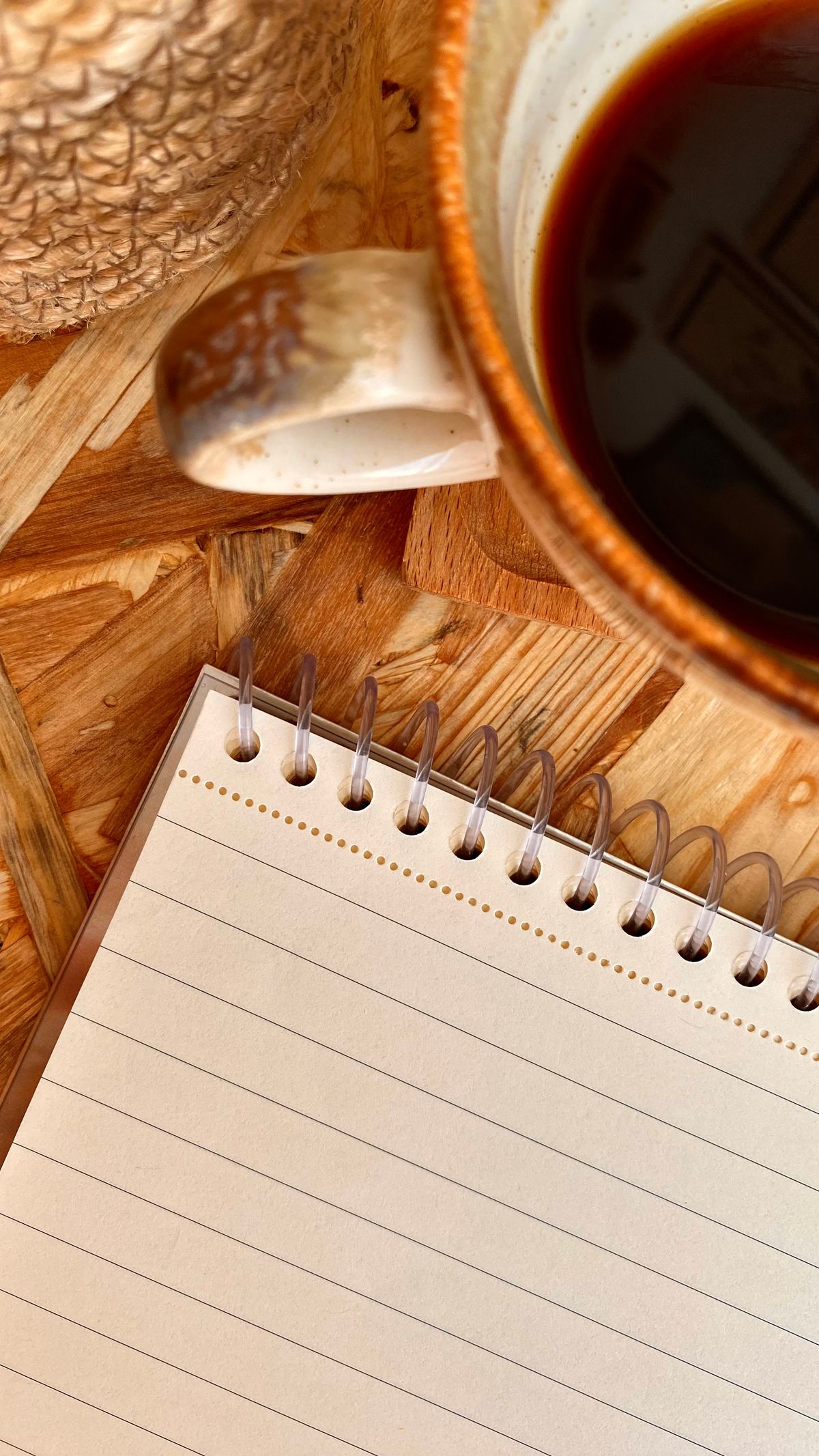 A spiral notebook and a cup of black coffee on a wooden table, the quiet morning routine of a writer