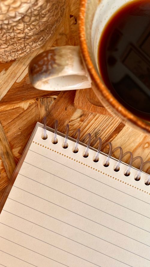 Free Top view of a coffee mug and spiral notebook on a wooden table, perfect for writing inspiration. Stock Photo